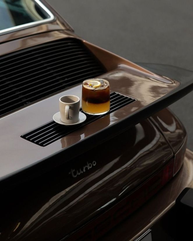 Espresso and a glass on the engine cover of a classic car