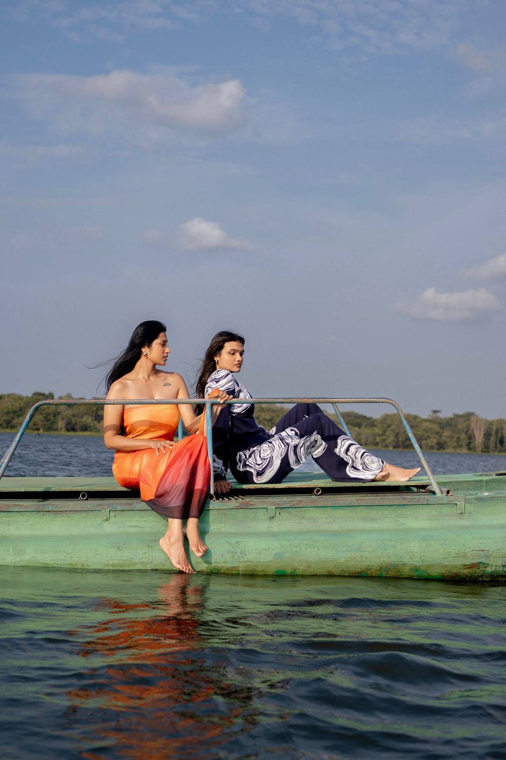 Two models in LAGIRI resort wear seated on a boat
